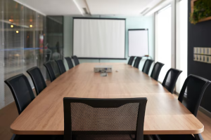 Salle de conférence moderne équipée par Artcast Technologies, avec table en bois et écran de projection.