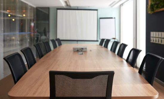 Salle de conférence moderne équipée par Artcast Technologies, avec table en bois et écran de projection.